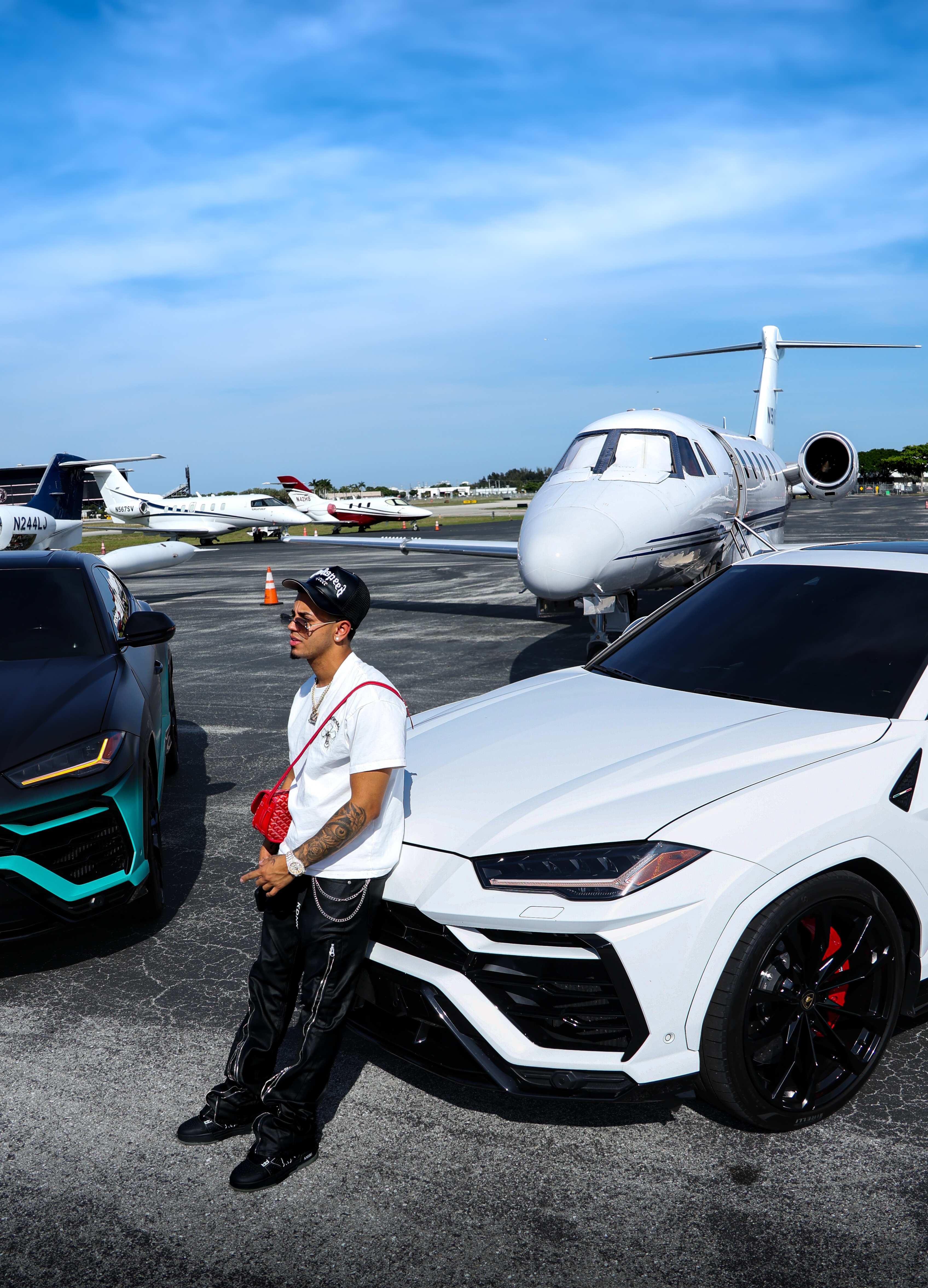 Man between two Lamborghini Urus SUVs on a private jet tarmac